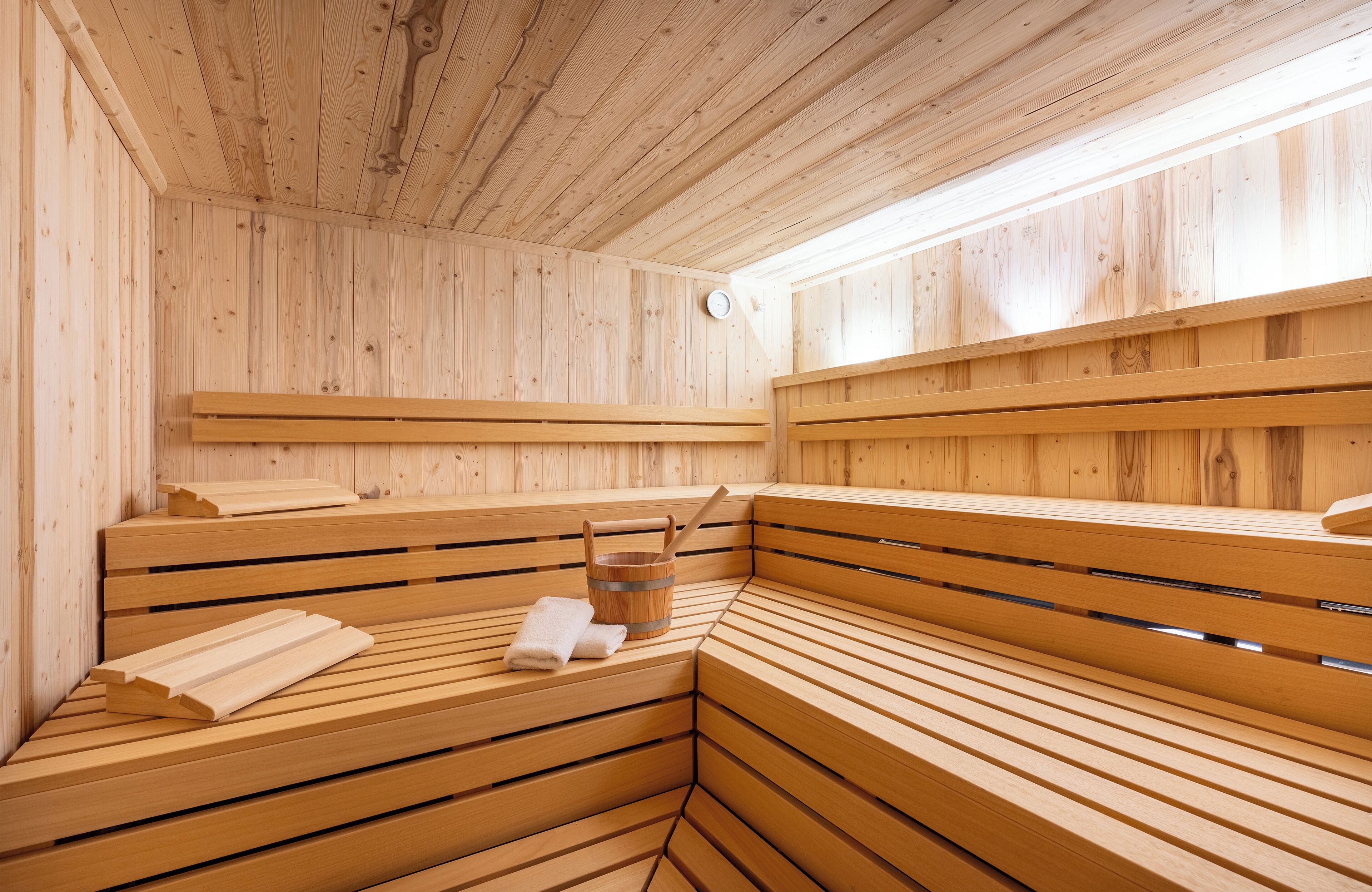 Un sauna en bois avec des bancs et un seau en bois.