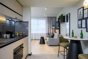 Una cocina moderna con azulejos negros, una cafetera y un comedor con una mesa redonda y sillas.
