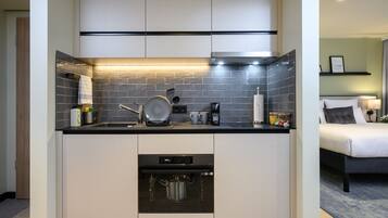 A compact kitchen with a dishwasher, a stove, and a coffee maker.
