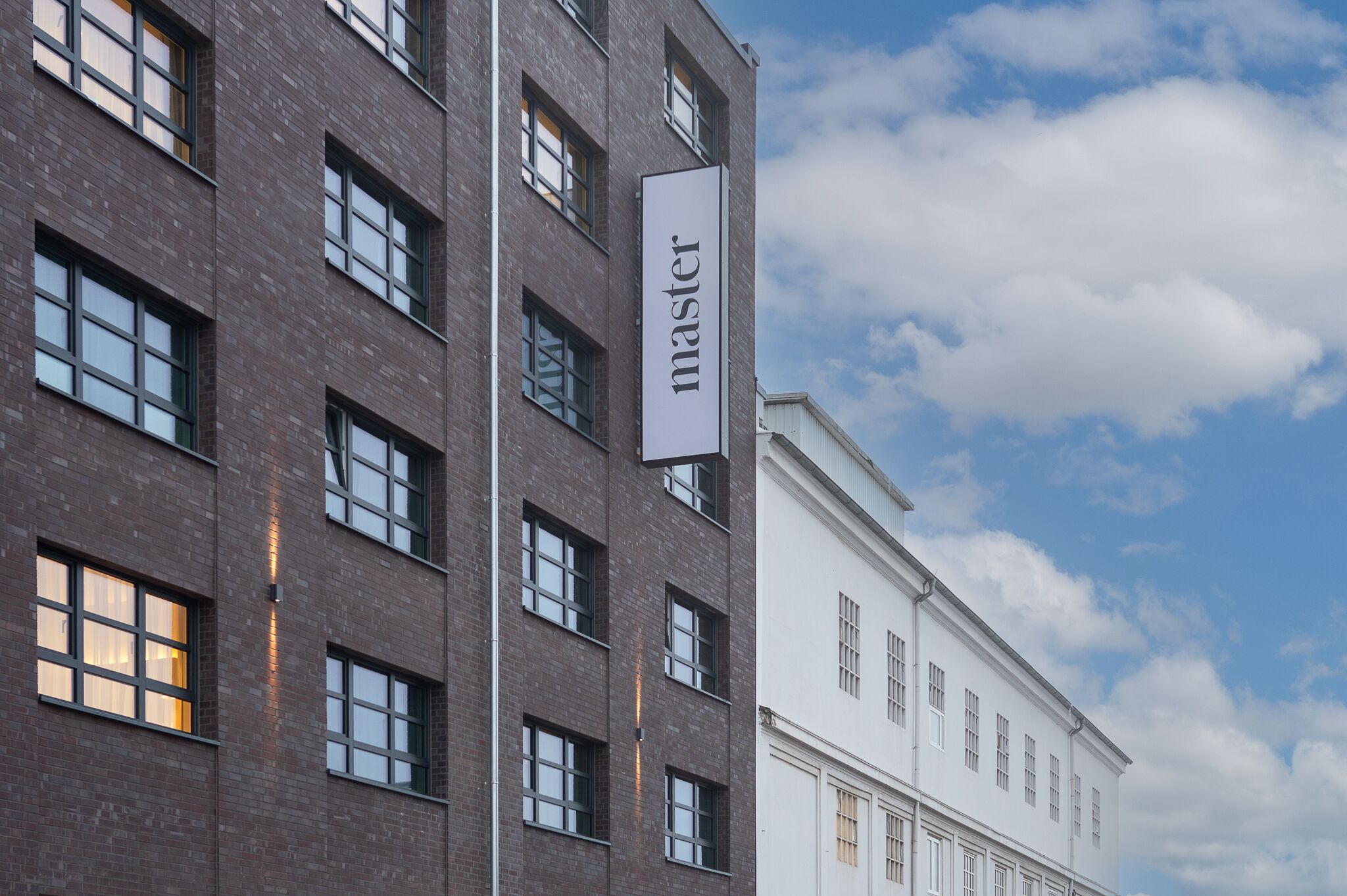 A modern building with a sign reading "master" on a vertical banner.