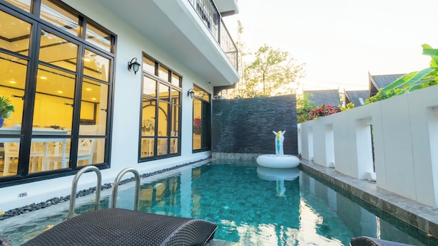 Um edifício moderno com amplas janelas, piscina e parede de pedra.