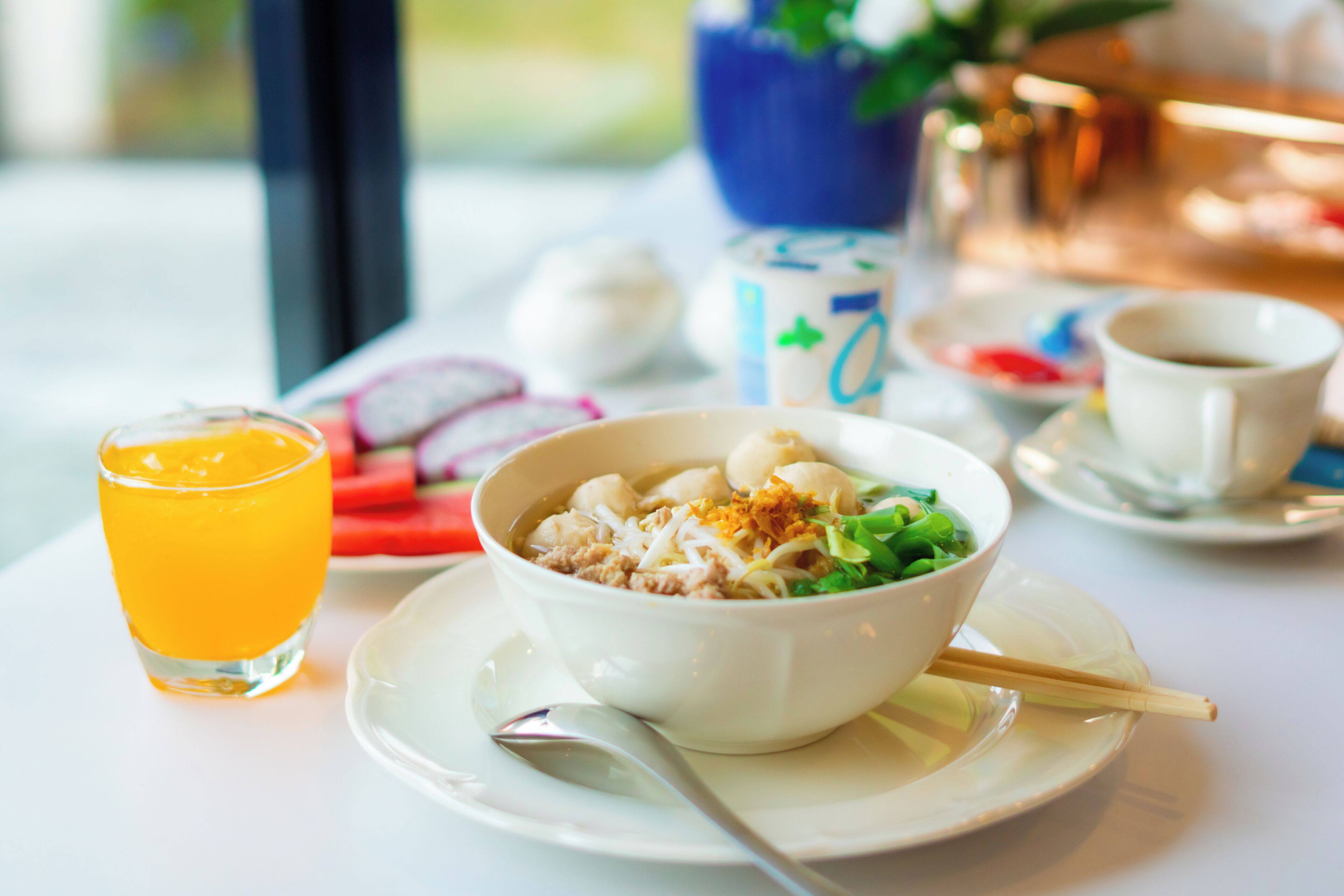 Una mesa con un tazón de comida, un vaso de jugo de naranja y una taza de café.