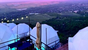 A view of a town from a high vantage point, with a large white tent in the foreground and a pinkish sky in the background. - Signagi Glamping (Sighnaghi)