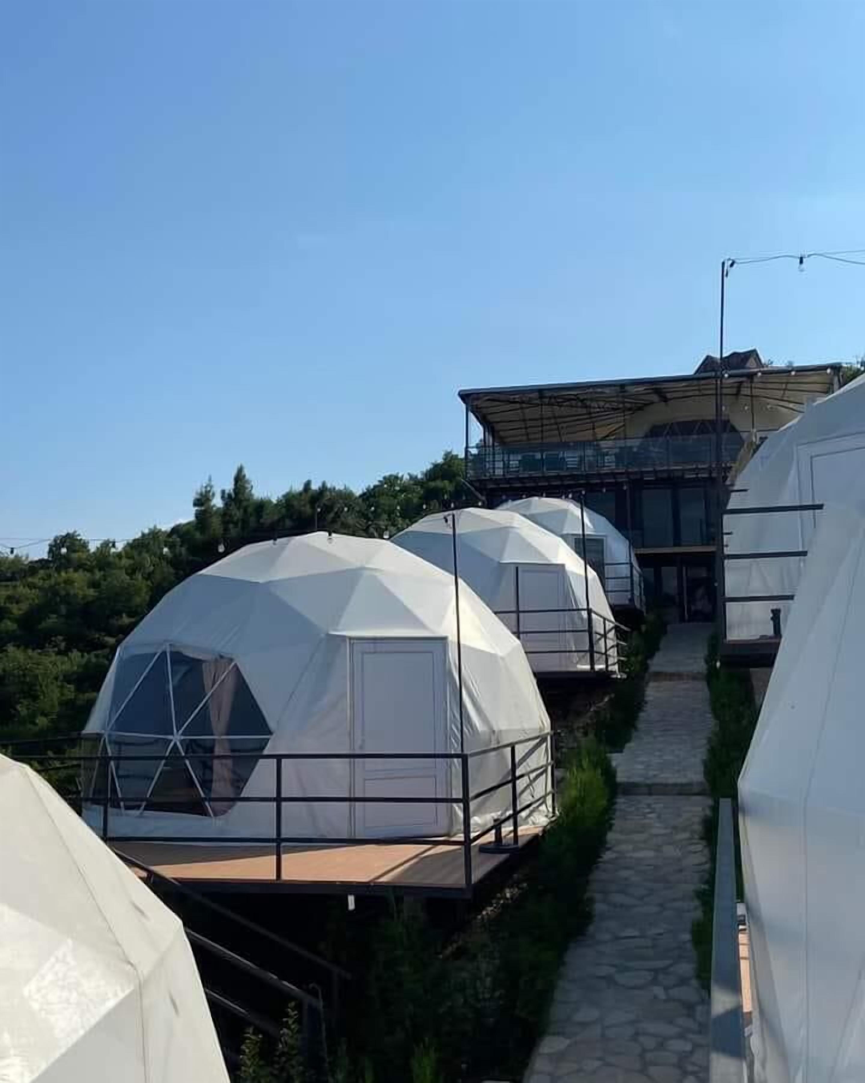 A row of dome-shaped tents with a central walkway leading to a covered area.