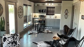 Un espace de vie moderne comprenant une cuisine, un coin repas et un salon agrémenté d’un tapis en peau de vache.