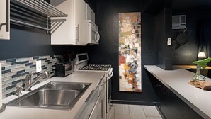 A modern kitchen with a stainless steel sink, a microwave, and a gas stove. - Montrose Ash Studio! Medical Center 03 (Houston)