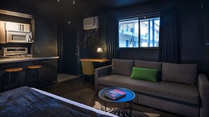 A compact hotel room with a kitchenette, a sofa with a green pillow, a small round table, and a bed. - Montrose Ash Studio! Medical Center 03 (Houston)