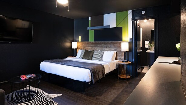 A modern hotel room with a large bed, a desk, and a ceiling fan. - Montrose Ash Studio! Medical Center 03 (Houston)