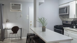 A modern kitchen with a white countertop, stainless steel appliances, and a potted plant.