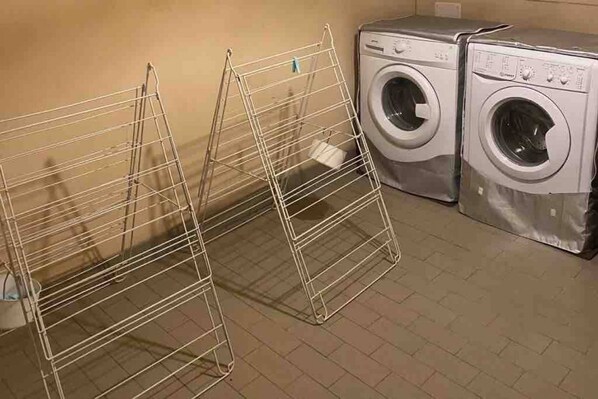 A laundry area with two washing machines and a metal drying rack.