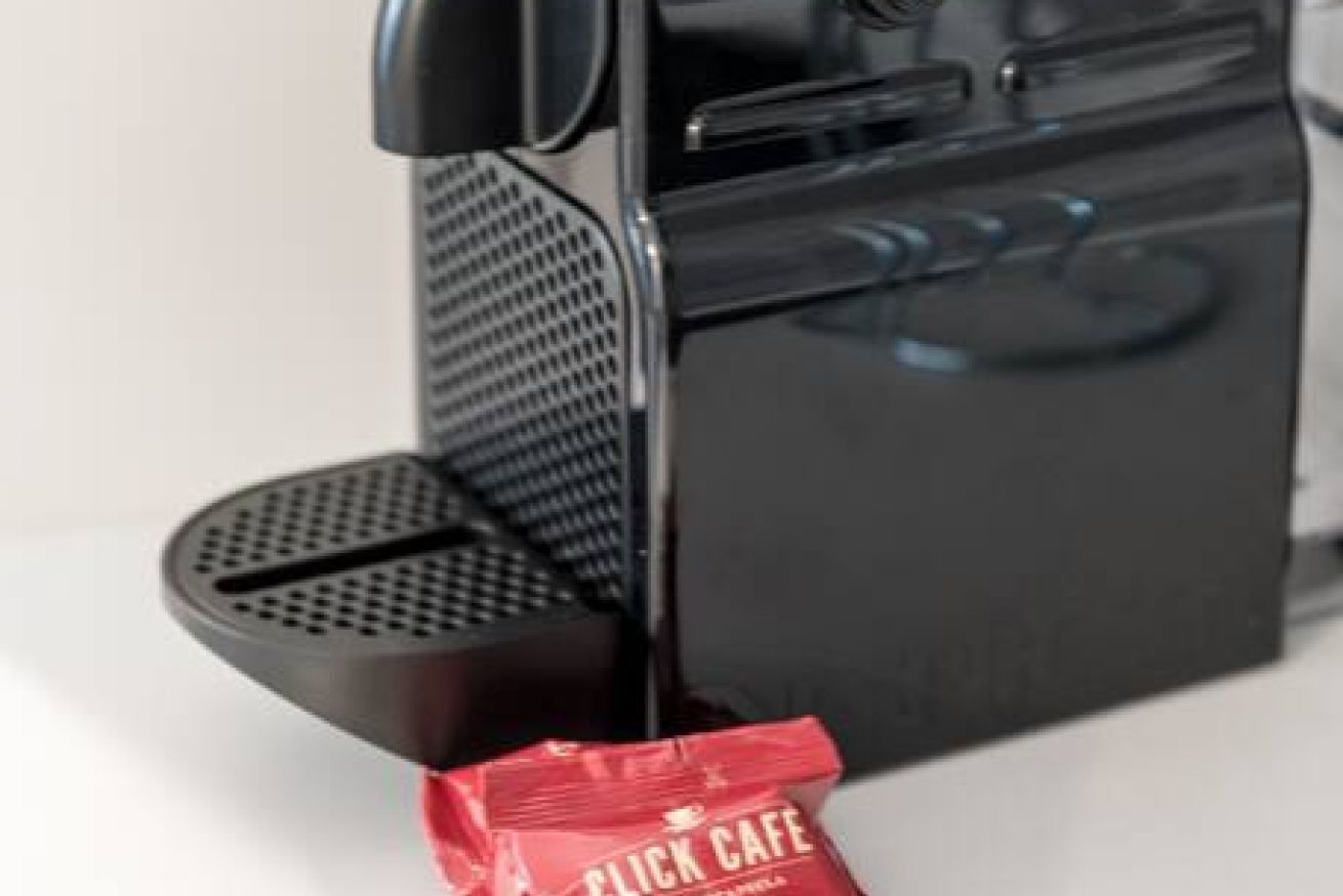 Una macchina per caffè con una confezione rossa di caffè etichettata 'CLICK CAFE' posata sopra.