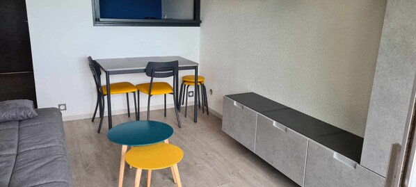 A compact room with a bed, a small table with chairs, a sofa, and a cabinet.