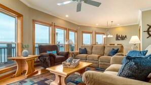 A spacious living room with a large window, a ceiling fan, and a view of the water. - New to Vrbo! "Dues Paid" Waterfront, Boat Dock, 3 Bedrm/2.5 Bath, Sleeps 6 (Dauphin Island)