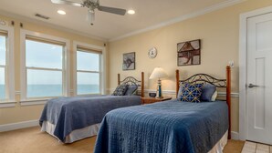A bedroom with two beds, a nightstand with a lamp, a clock, and artwork on the wall. - New to Vrbo! "Dues Paid" Waterfront, Boat Dock, 3 Bedrm/2.5 Bath, Sleeps 6 (Dauphin Island)