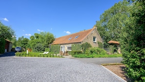 A house with a gravel driveway, a small garden, and a neighboring building. - Cosy holiday home in Flanders Fields and at 10min from the sea. Pets welcome! (Alveringem)