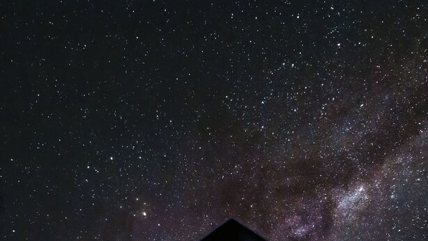 A building with a brick facade and a tower-like structure against a starry night sky. - Casa Cumbre: Un hospedaje único en Mérida, con la mejor vista a la Sierra Nevada (Merida)