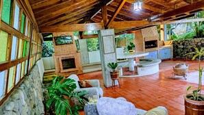 A cozy outdoor seating area with stone walls, a brick fireplace, and potted plants. - Casa Cumbre: Un hospedaje único en Mérida, con la mejor vista a la Sierra Nevada (Merida)