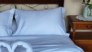 A neatly made bed with white linens and a heart-shaped towel arrangement. - Casa Cumbre: Un hospedaje único en Mérida, con la mejor vista a la Sierra Nevada (Merida)
