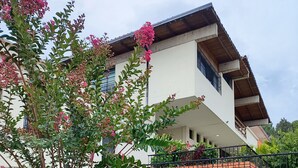 A modern two-story house with a stone wall in the foreground and a balcony with a metal railing. - Casa Cumbre: Un hospedaje único en Mérida, con la mejor vista a la Sierra Nevada (Merida)