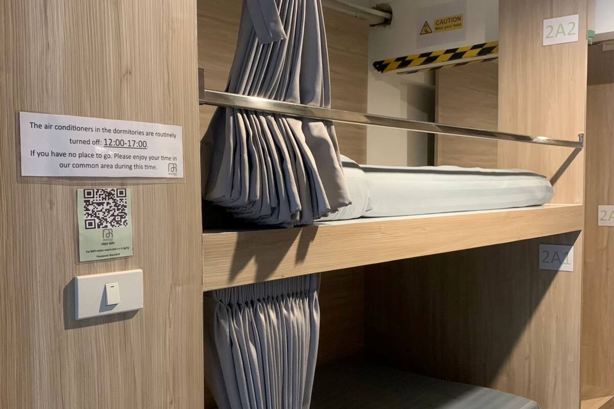 A bunk bed with curtains, a QR code, and a sign about air conditioner hours.