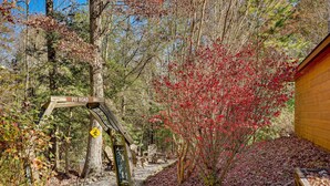 A wooden signpost labeled 'Pit Road' in a forested area with a wooden building and a path covered with fallen leaves.