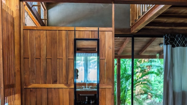 A wooden interior with a high ceiling and a view of greenery outside. - Playa Pelada Beachfront Bungalow at villas Ecositas Nosara (Provincia de Guanacaste)