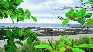 A coastal view with rocky shoreline, greenery, and a clear sky. - Playa Pelada Beachfront Bungalow at villas Ecositas Nosara (Provincia de Guanacaste)
