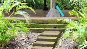 A covered wooden structure with stone steps leading to a platform, surrounded by lush greenery. - Playa Pelada Beachfront Bungalow at villas Ecositas Nosara (Provincia de Guanacaste)