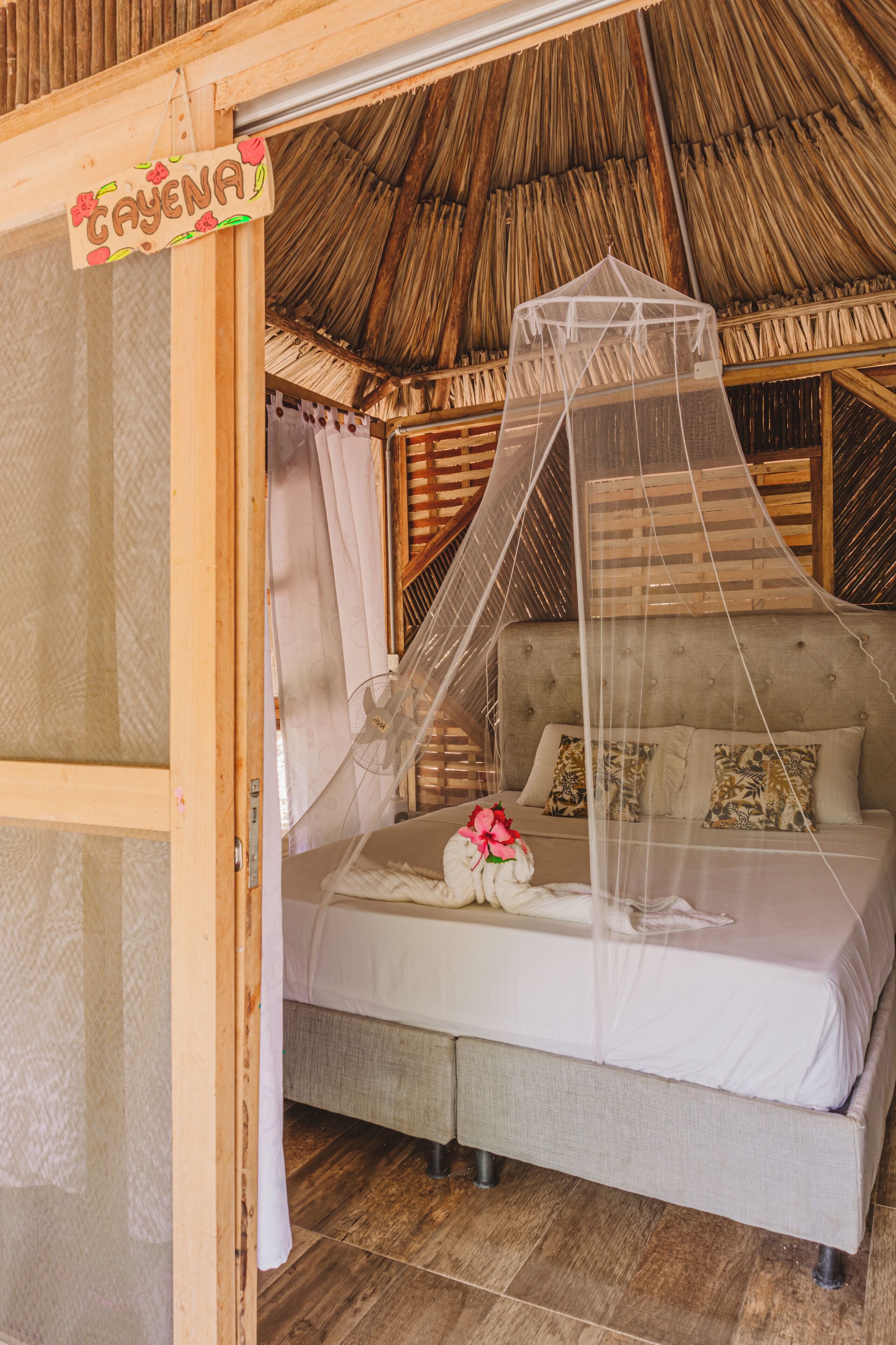 A bed with a canopy, a sign reading "CAYENA", and a thatched roof.