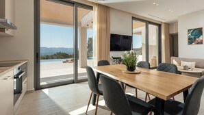 A modern dining area with a wooden table, grey chairs, and a potted plant.