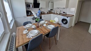 A modern kitchen with white cabinets, a built-in microwave, and a washing machine. - Bright, newly renovated TOP flat in a central location (Osnabrück)