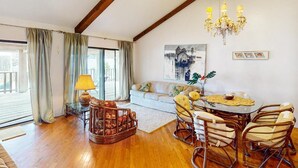 A spacious living area with a wooden floor, a round dining table with chairs, a sofa, and a chandelier. - Channel-Front Port Isabel Family Home. Gulf/Bay Fishing and Close to SPI Beach! (Port Isabel)