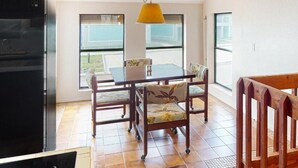 A kitchen with a black refrigerator, a dining table with four chairs, and a yellow hanging lamp. - Channel-Front Port Isabel Family Home. Gulf/Bay Fishing and Close to SPI Beach! (Port Isabel)