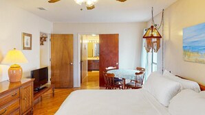 A bedroom with a bed, a desk with a lamp, a television, and a dining area with chairs and a table. - Channel-Front Port Isabel Family Home. Gulf/Bay Fishing and Close to SPI Beach! (Port Isabel)