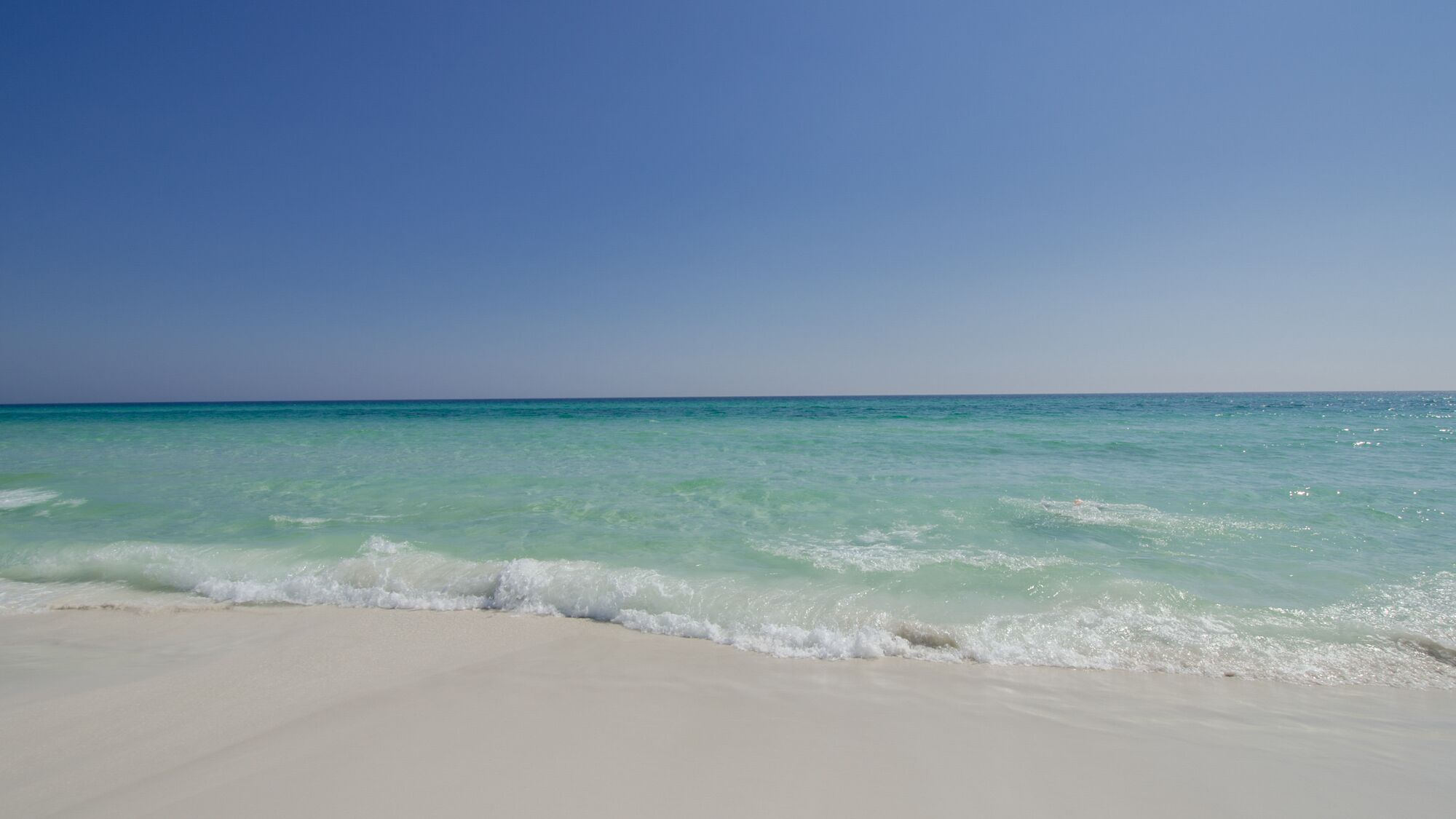 Ein Strand mit klarem türkisblauem Wasser und weißem Sand.