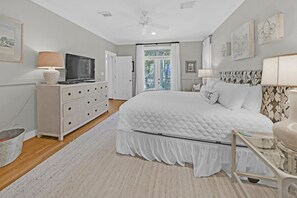 Ein Schlafzimmer mit Bett, Kommode, Fernseher und Bildern an den Wänden.