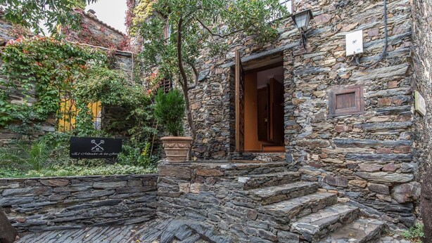A stone building with a wooden door and steps leading to a garden area. - El Mirador de las Jaras (Patones)