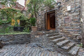 Un edificio de piedra con una puerta de madera y escalones que conducen a un jardín.