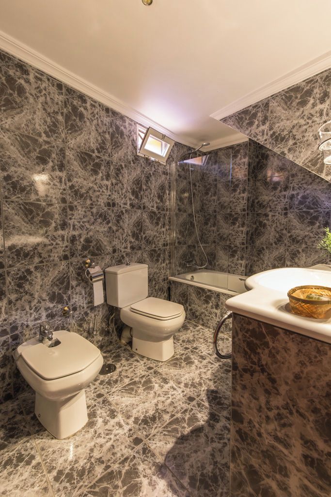 Une salle de bain avec un sol en marbre, des toilettes, un bidet, une baignoire et un meuble-lavabo avec un miroir.