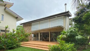 Une maison à deux étages dotée d’un patio couvert, d’une façade en pierre et d’une pelouse bien entretenue.