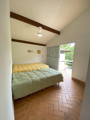 Ein Schlafzimmer mit Bett, Deckenventilator und Blick ins Freie.