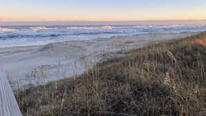 Une plage avec des vagues, du sable et de l’herbe.