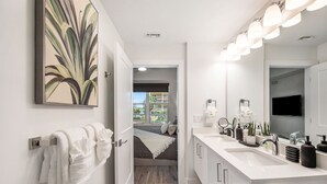 Une salle de bain moderne avec un grand miroir, deux vasques et un porte-serviettes.