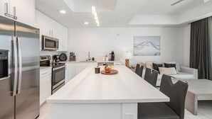 Une cuisine moderne dotée d’appareils électroménagers en acier inoxydable, d’un îlot central et d’un coin repas avec un canapé et des chaises.