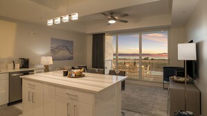 Une cuisine moderne dotée d’un grand îlot central, d’un coin repas offrant une vue agréable et d’un balcon d’où l’on peut admirer le coucher du soleil.