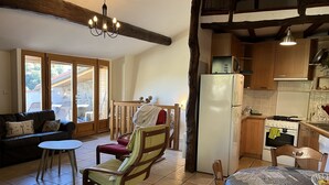 Ein gemütliches Wohnzimmer mit einer Couch, einem kleinen Tisch und einem Sessel. Es gibt eine Küchenzeile mit Kühlschrank, Herd und Schränken.