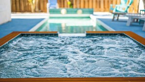 A hot tub with a wooden frame, surrounded by a wooden fence and outdoor furniture. - LJ's Cottages 3 - BALCONY BEACH POOL SAND SUNSETS (Sarasota)