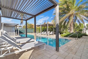 A pool area with lounge chairs and a pergola structure. - Beautiful 3BR Townhouse near Palm Beach (Noord)