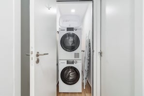A laundry room with two stacked washing machines and a drying rack.