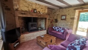 A rustic living room with a stone wall, a fireplace, a sofa, and a television. - Gite Tout Confort 4personnes Avec Piscine, Proche Lot, Dordogne, Lot et Garonne (Marminiac)